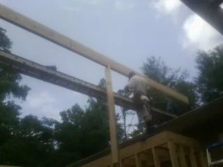 Carpenter setting a ridge beam over a new addition frame — Ice Dam Removal by Roofing Brothers in Kenansville