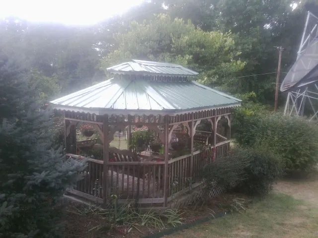 Green metal roof on a backyard gazebo surrounded by garden beds in Kenansville